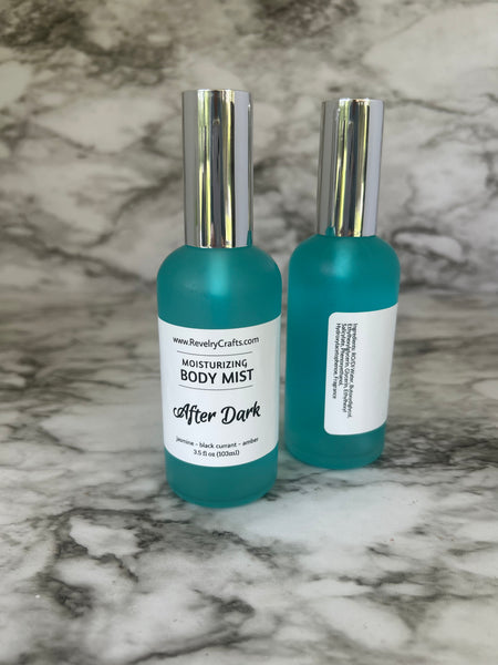 Two teal body mist bottles with silver caps and white labels, labeled 'After Dark Moisturizing Body Mist' by Beauty Cultist, placed on a gray and white marble surface.